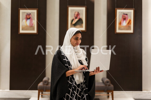 مرأة خليجية سعودية في داخل الفندق السياحي ، إستخدام جهاز الحاسوب المحمول لإنجاز المهام ، مفهوم التكنولوجيا وإستخدام أجهزة تقنية حديثة، العمل عن بعد ، مهن ووظائف ، جلسة عمل ، تصفح الإنترنت ، رحلة عمل، سياحة وفندقة ، التسويق الإلكتروني