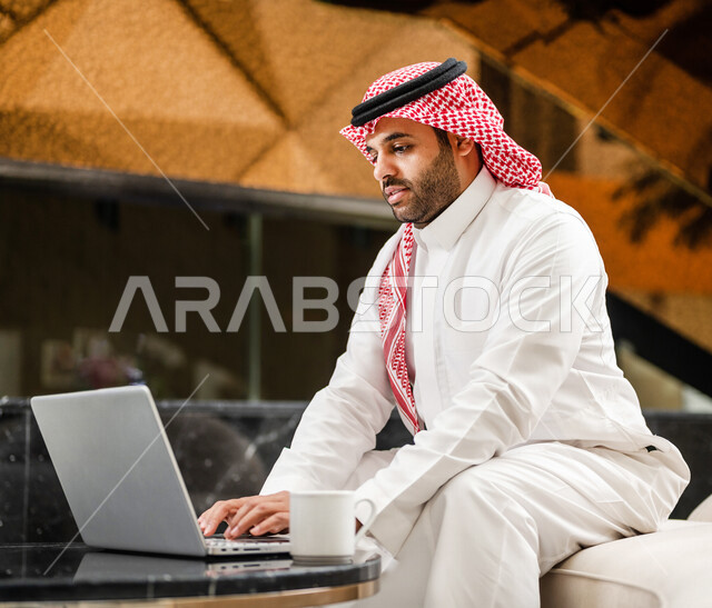 رجل خليجي سعودي بداخل احدى الفنادق السياحية ، إستخدام جهاز الحاسوب المحمول لإنجاز المهام ، مفهوم التكنولوجيا وإستخدام أجهزة تقنية حديثة، العمل عن بعد ، مهن ووظائف ، جلسة عمل ، مفهوم إدارة الأعمال، رحلة عمل، سياحة وفندقة ، التسويق الإلكتروني