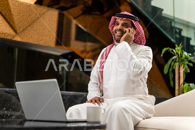 رجل خليجي سعودي بداخل الفنادق السياحية ، يقوم بإجراء مكالمة هاتفية عبر الجوال ، إستخدام جهاز الحاسوب المحمول لإنجاز المهام، إستخدام أجهزة تقنية حديثة، العمل عن بعد ، مهن ووظائف ، جلسة عمل، مفهوم إدارة الأعمال، سياحة وفندقة، التسويق الإلكتروني