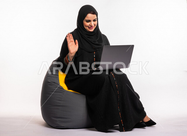  بورتريه لإمرأه عربيه سعوديه خليجيه تجلس على أريكه مريحه, انجاز مهام العمل عبر الحاسوب, إدارة المشاريع عن بعد, اللعب على اللابتوب, إجراء مكالمات فيديو عبر الإنترنت, مشاهدة فلم عبر الجهاز المحمول, تسليه وترفيه, قضاء وقت ممتع