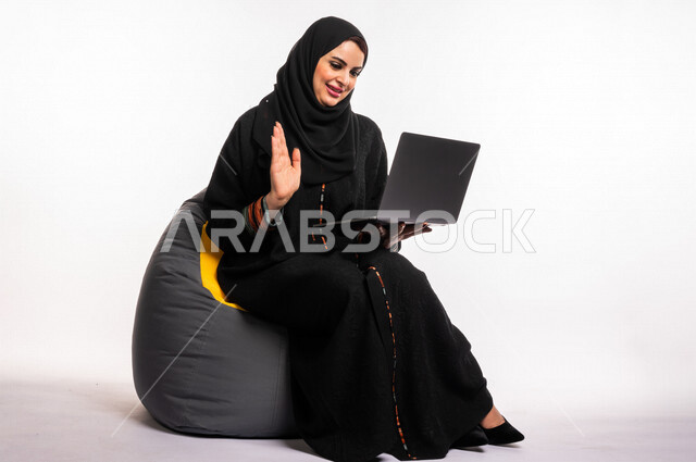  بورتريه لإمرأه عربيه سعوديه خليجيه تجلس على أريكه مريحه, انجاز مهام العمل عبر الحاسوب, إدارة المشاريع عن بعد, اللعب على اللابتوب, إجراء مكالمات فيديو عبر الإنترنت, مشاهدة فلم عبر الجهاز المحمول, تسليه وترفيه, قضاء وقت ممتع