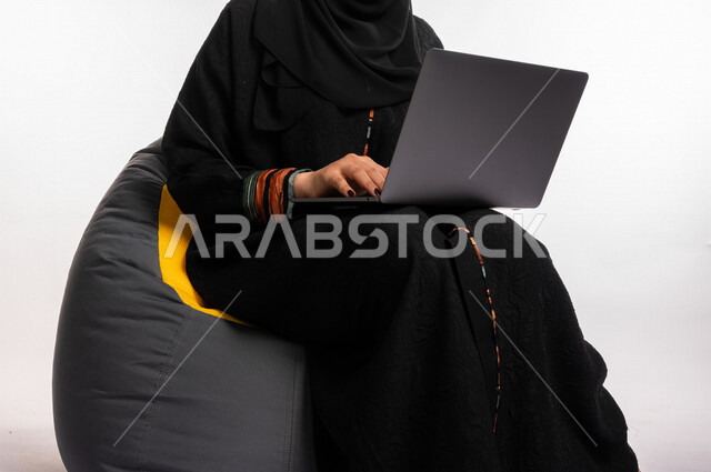  بورتريه لإمرأه عربيه سعوديه خليجيه تجلس على أريكه مريحه, انجاز مهام العمل عبر الحاسوب, إدارة المشاريع عن بعد, اللعب على اللابتوب, إجراء مكالمات فيديو عبر الإنترنت, مشاهدة فلم عبر الجهاز المحمول, تسليه وترفيه, قضاء وقت ممتع