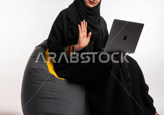  بورتريه لإمرأه عربيه سعوديه خليجيه تجلس على أريكه مريحه, انجاز مهام العمل عبر الحاسوب, إدارة المشاريع عن بعد, اللعب على اللابتوب, إجراء مكالمات فيديو عبر الإنترنت, مشاهدة فلم عبر الجهاز المحمول, تسليه وترفيه, قضاء وقت ممتع