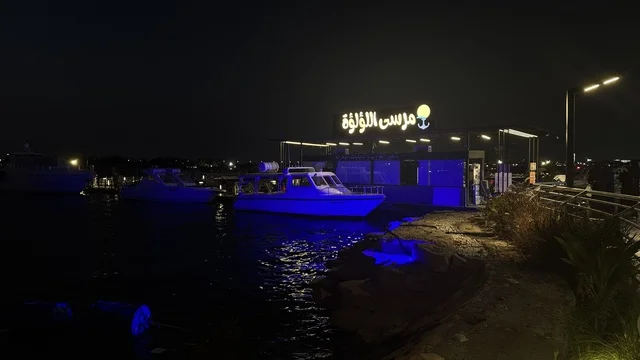 Guidance signs at the Abhur waterfront on the northern corniche of Jeddah, Saudi Arabia, a tourist and recreational marine destination, a coastal promenade with open views of the Red Sea, restaurants and cafes overlooking the waterfront, various recreational activities, and a calm and distinctive family atmosphere.