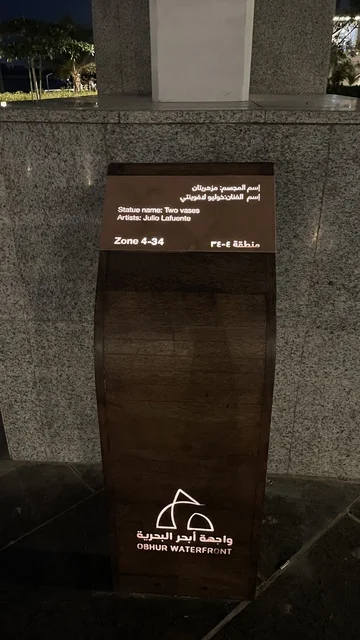 An artistic sculpture of two vases at the Abhur waterfront on the northern corniche of Jeddah, Saudi Arabia, a tourist and recreational marine destination, a coastal promenade with open views of the Red Sea, urban projects that enhance the waterfront, and various recreational activities.