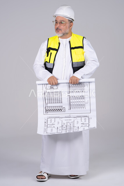 مهندس إماراتي يحمل مخطط بناء في استوديو
