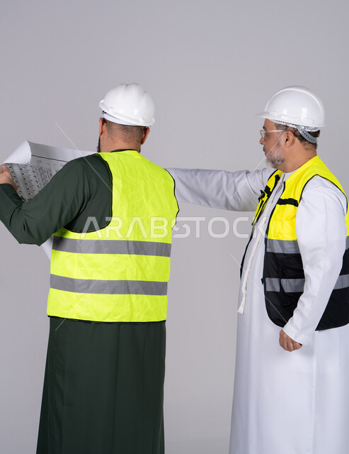 مهندسان إماراتيان يراجعان المخططات الهندسية بزي السلامة
