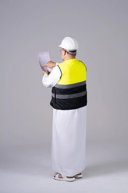 Emirati Engineer in Safety Gear Reviewing Blueprints