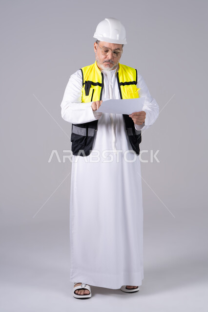 مهندس إماراتي بملابس السلامة يقرأ مخطط ورقي