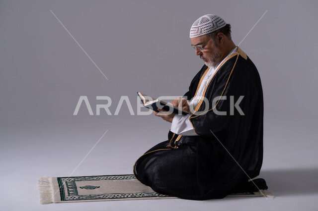رجل إماراتي بالبشت يقرأ القرآن على سجادة الصلاة
