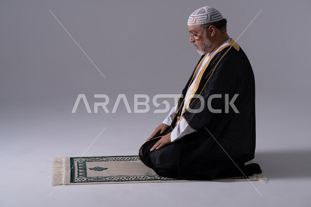 رجل إماراتي يصلي على السجادة في الاستوديو
