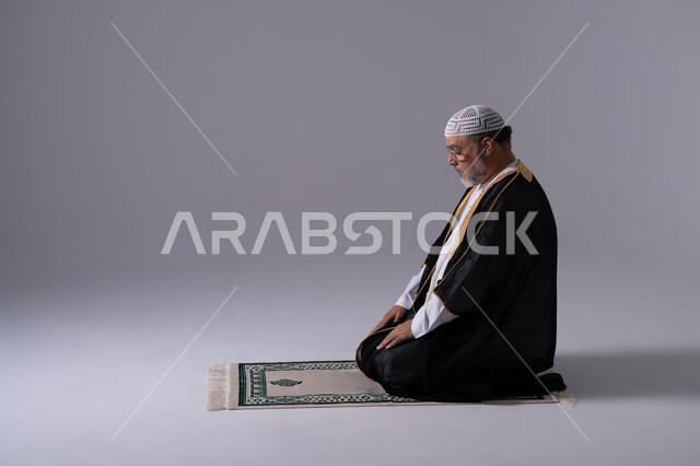 رجل إماراتي يصلي باللباس التقليدي على خلفية بيضاء
