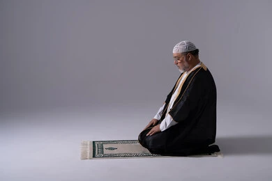 رجل إماراتي يصلي باللباس التقليدي على خلفية بيضاء