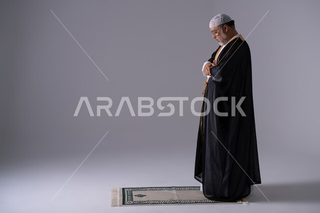 رجل إماراتي يصلي بالبشت الأسود التقليدي