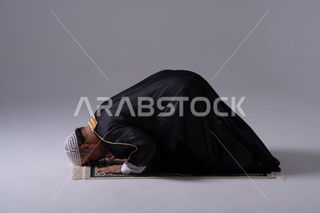 رجل إماراتي يصلي في وضعية السجود خلفية استوديو
