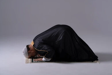 رجل إماراتي يصلي في وضعية السجود خلفية استوديو