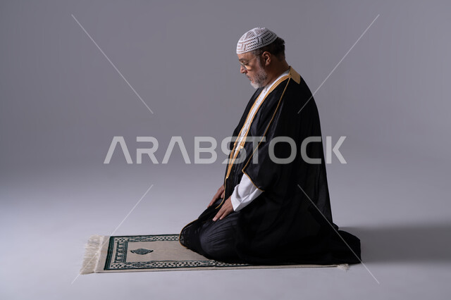 رجل إماراتي يصلي على السجادة في الاستوديو