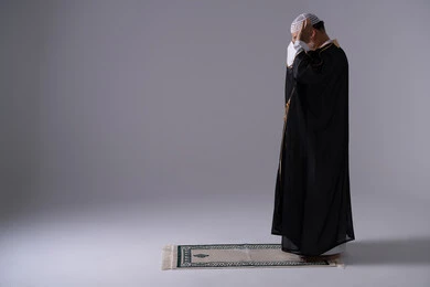 Emirati Man in Bisht Praying on Rug Studio Background
