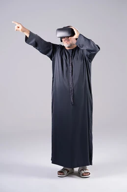 رجل إماراتي بالكندورة السوداء يستخدم نظارة الواقع الافتراضي