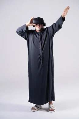 رجل إماراتي بالكندورة يرتدي نظارة واقع افتراضي في استوديو