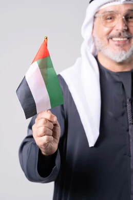 Emirati Man in Traditional Dress Holding UAE Flag