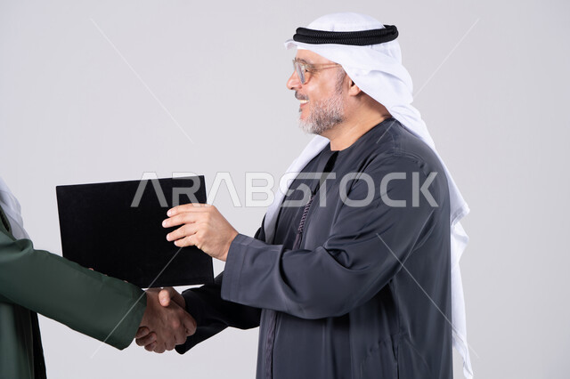 رجل أعمال إماراتي يصافح ويستلم ملف عقد