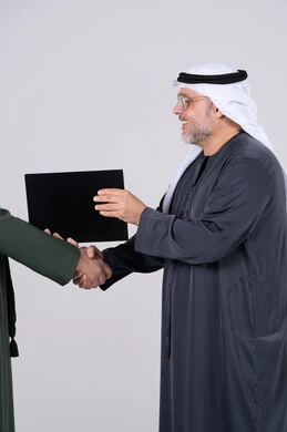 رجل أعمال إماراتي يتصافح مع مجلد مستندات