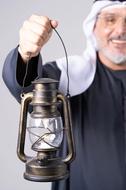 رجل إماراتي يمسك فانوساً تراثياً لقطة قريبة