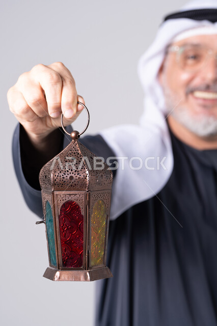 رجل إماراتي يرتدي الزي التقليدي يحمل فانوس رمضان الملون