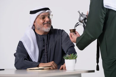 Emirati Man Receiving Arabic Coffee at Office Desk