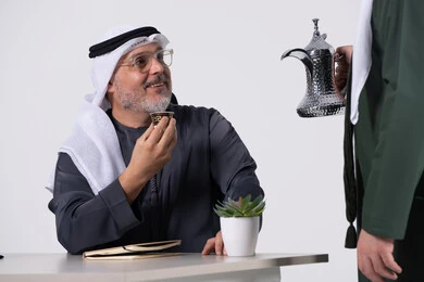 رجل إماراتي يشرب القهوة العربية في مكتب عمل