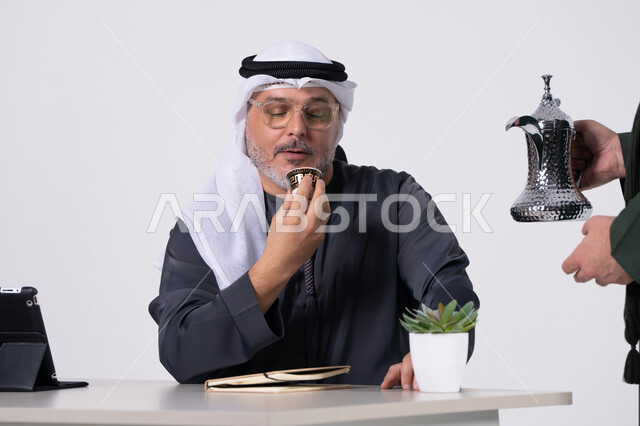 Emirati Man Drinking Arabic Coffee at Office Desk