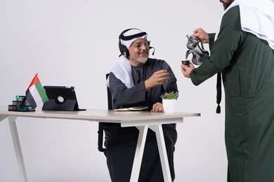 رجل إماراتي يتناول القهوة العربية في مكتب العمل