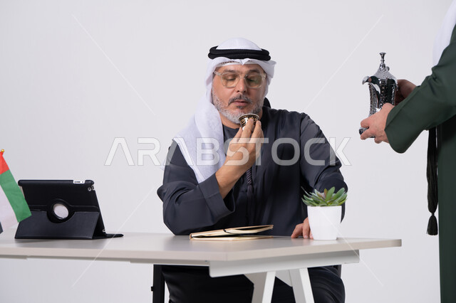 رجل إماراتي يشرب القهوة العربية في مكتب العمل