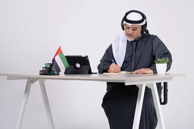 رجل أعمال إماراتي على مكتب مع علم الإمارات