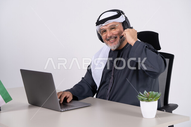 رجل أعمال إماراتي يرتدي سماعة رأس في المكتب