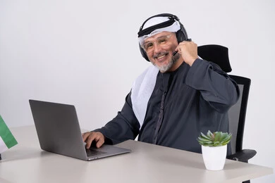 رجل أعمال إماراتي يرتدي سماعة رأس في المكتب