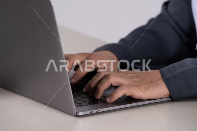 يدي رجل أعمال إماراتي يكتب على لوحة مفاتيح الكمبيوتر