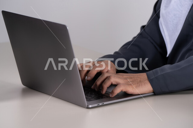 رجل إماراتي يكتب على حاسوب محمول لقطة قريبة