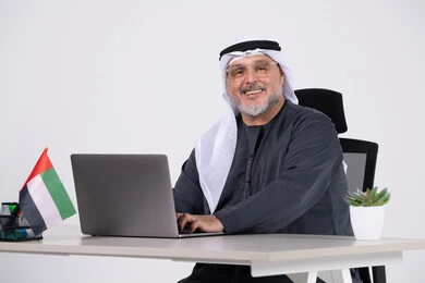 رجل أعمال إماراتي يعمل على اللابتوب في المكتب