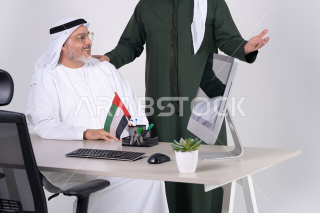 رجال أعمال إماراتيون يعملون على كمبيوتر مكتبي