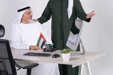 رجال أعمال إماراتيون يعملون على كمبيوتر مكتبي