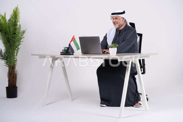 رجل أعمال إماراتي يعمل على المحمول في مكتب عصري