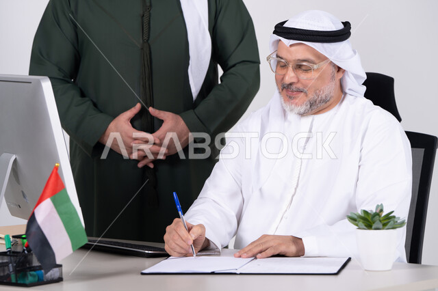 رجل أعمال إماراتي يوقع مستندات في المكتب الإمارات