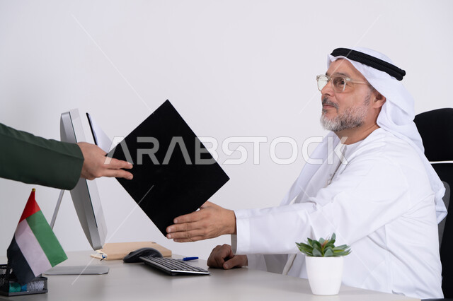 رجل أعمال إماراتي يستلم ملفاً في مكتب أبيض