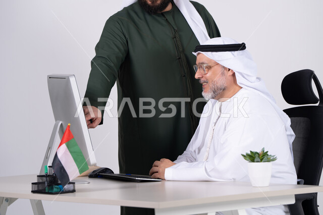 رجال أعمال إماراتيون يعملون على الكمبيوتر في المكتب