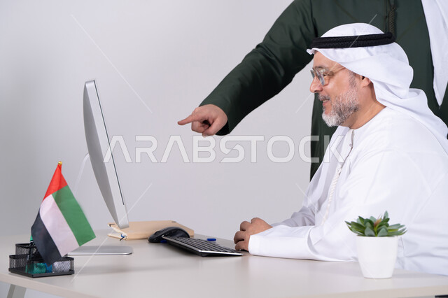 رجل أعمال إماراتي يعمل على كمبيوتر مكتبي