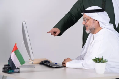 رجل أعمال إماراتي يعمل على كمبيوتر مكتبي