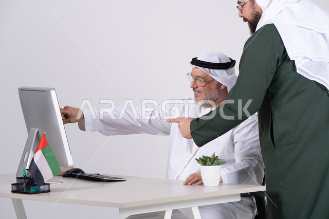 رجال أعمال إماراتيون يعملون على الكمبيوتر في المكتب