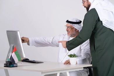 رجال أعمال إماراتيون يعملون على الكمبيوتر في المكتب